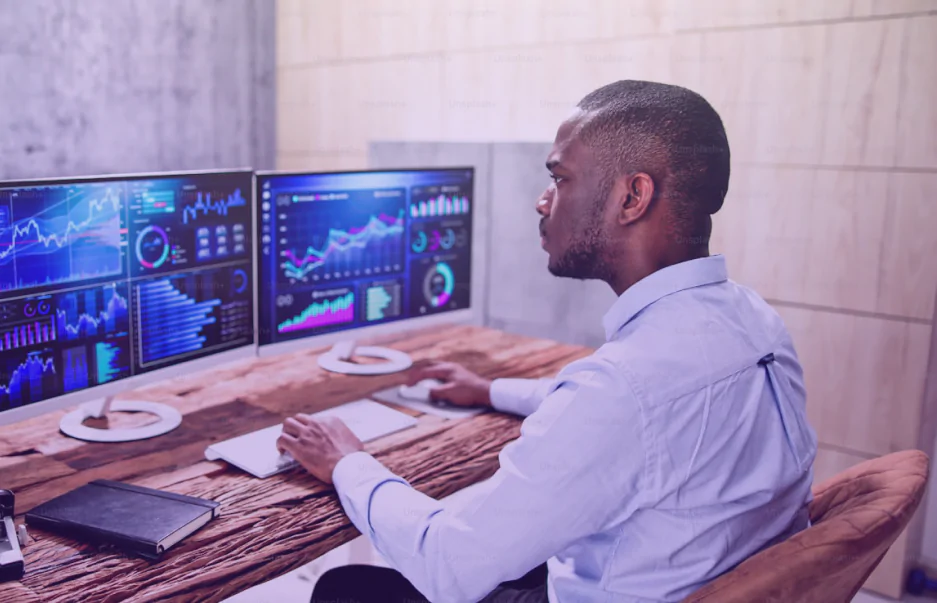 Analista acompanhando painéis de dados e indicadores em múltiplos monitores
